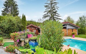 Una zona junto a la piscina con una cabaña de madera y una jardinera grande.