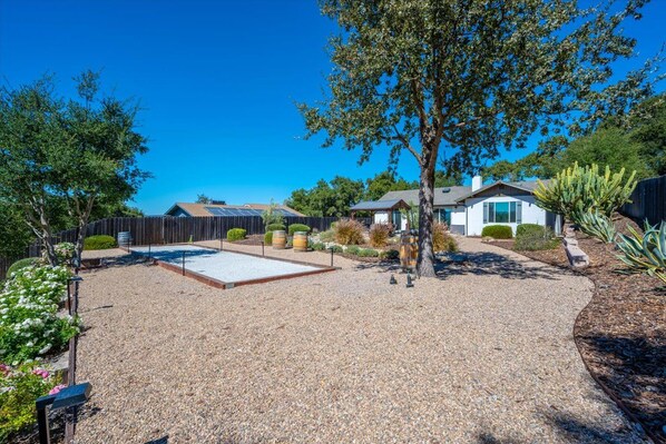 A backyard with a patio, a tree, and a house in the background.