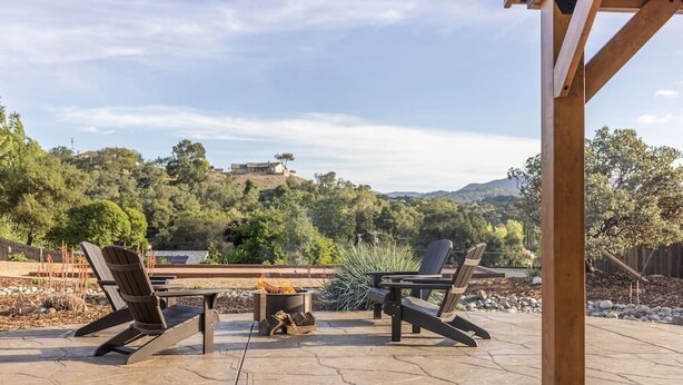 An outdoor patio with two Adirondack chairs, a fire pit, and a pergola structure. - Picturesque Rosemary Retreat (California)