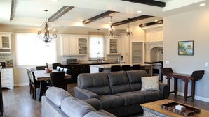 A spacious living room with a grey sectional sofa, a wooden coffee table, and a chandelier. - Picturesque Rosemary Retreat (California)