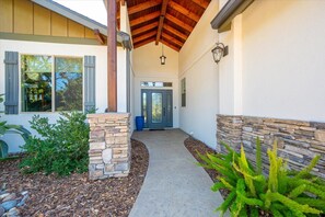 A house with a stone entrance, a covered porch, and a pathway leading to the front door.