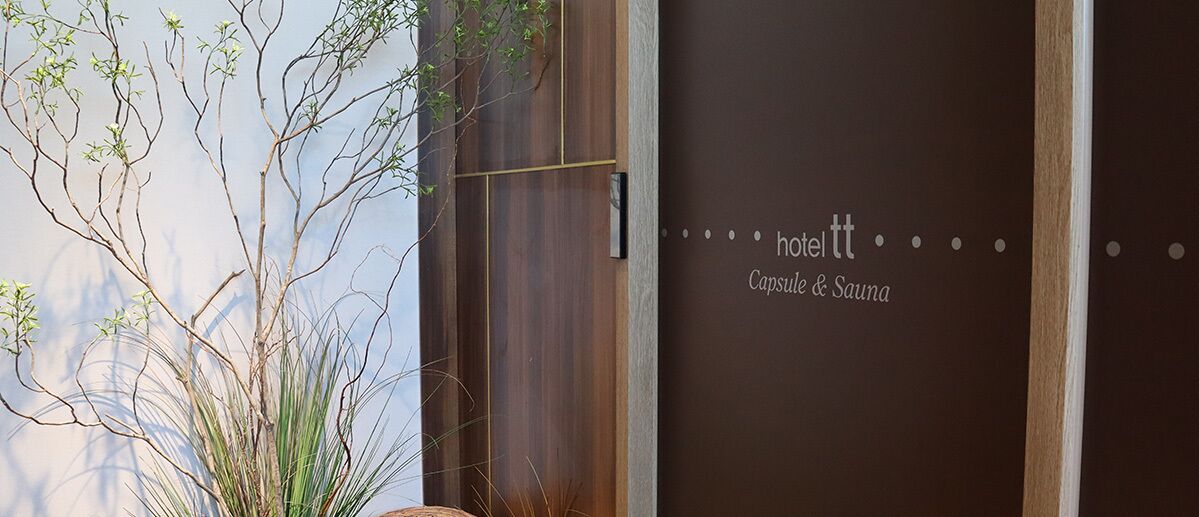 A door with the text "hotel tt Capsule & Sauna" indicating a hotel with a capsule and sauna facility.