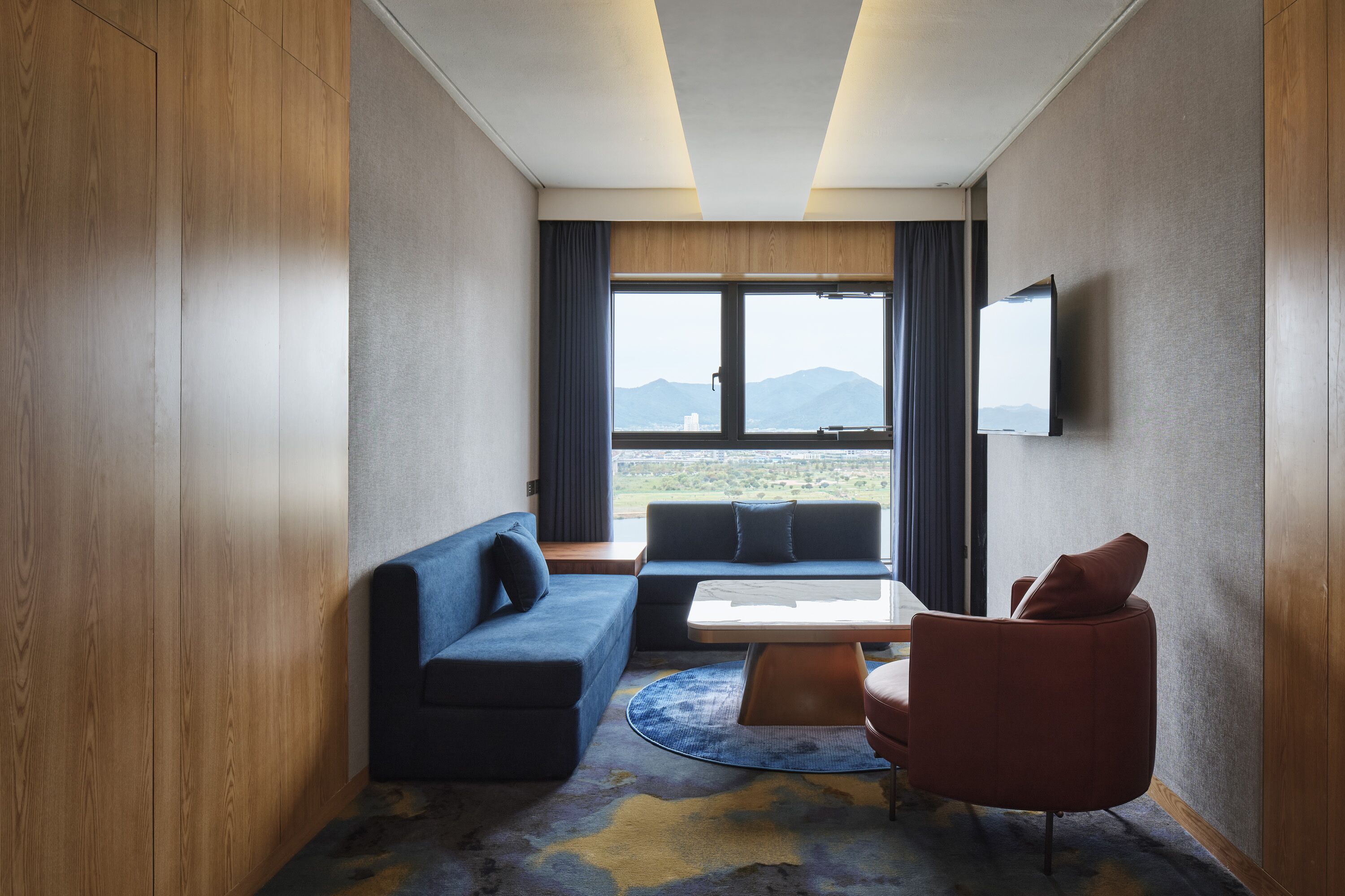 A modern hotel room with a sofa, armchair, and a small table.