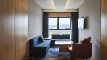 A modern hotel room with a sofa, armchair, and a small table.