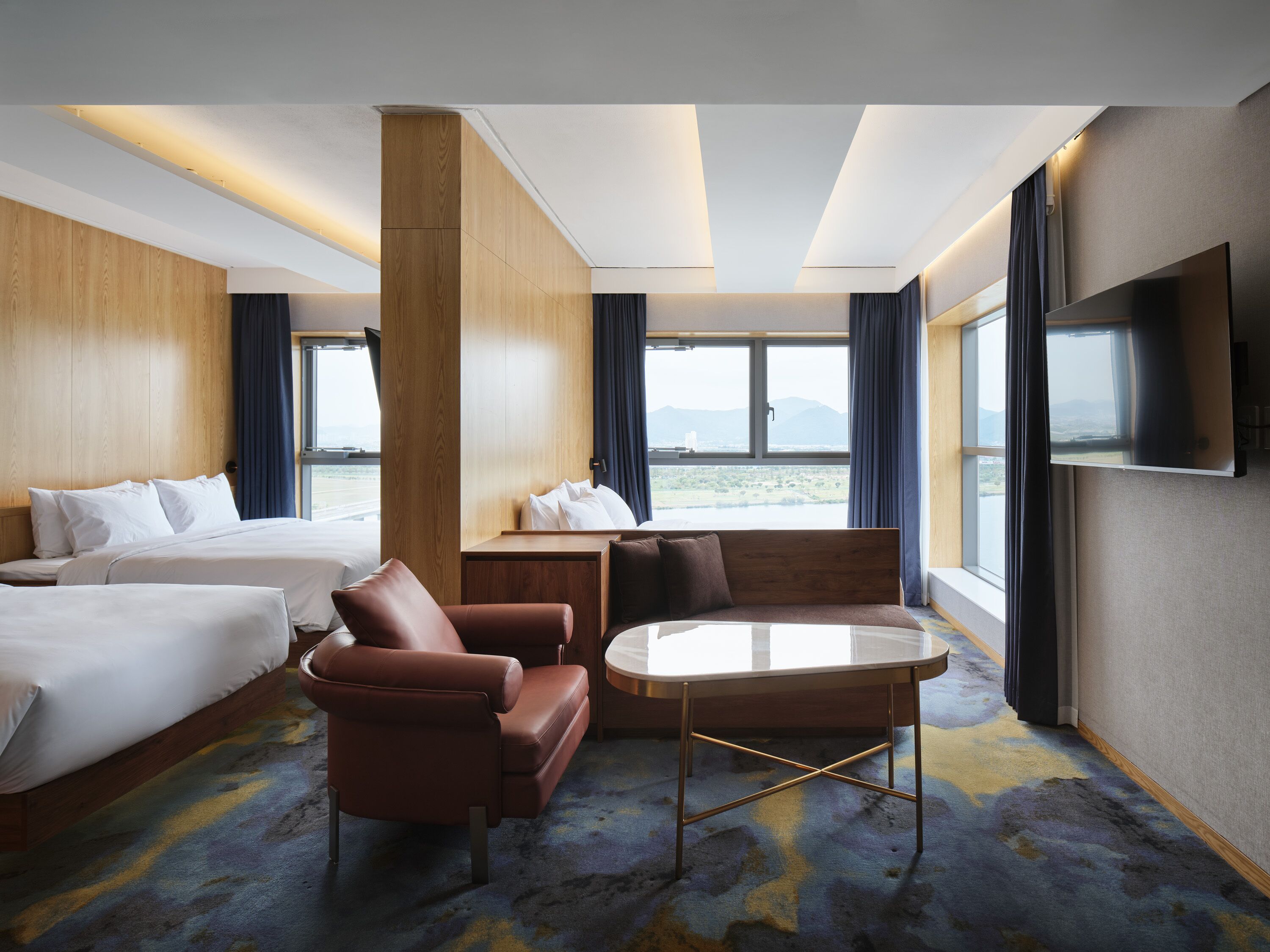 Ein Hotelzimmer mit zwei Betten, einem Sofa, einem Tisch und einem Fernseher.