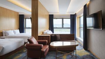 Ein Hotelzimmer mit zwei Betten, einem Sofa, einem Tisch und einem Fernseher.