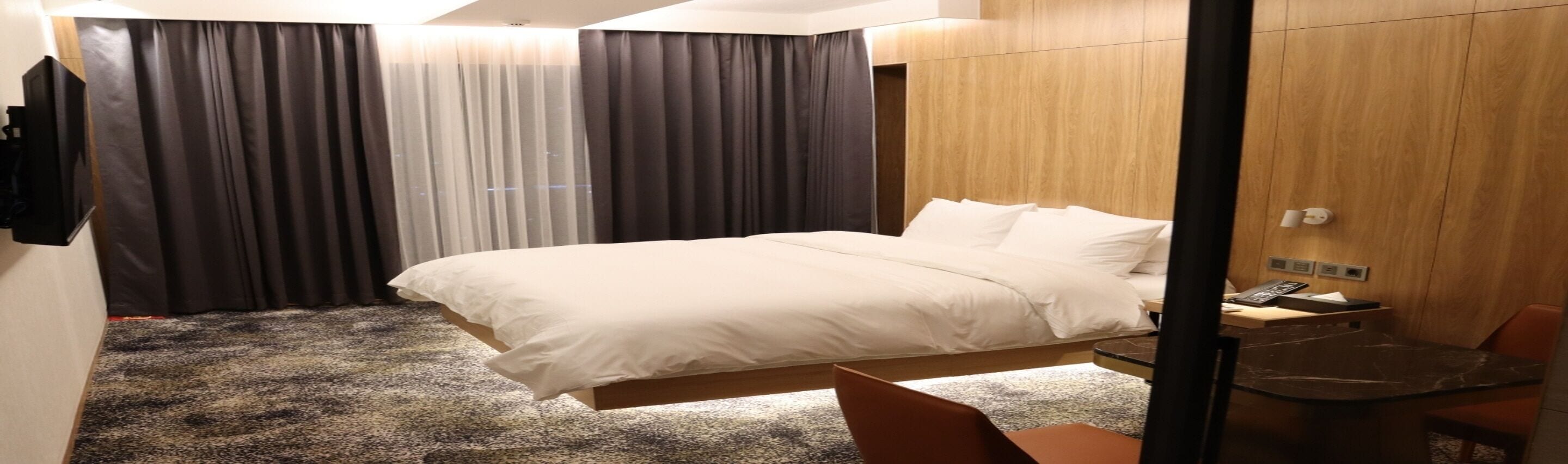 Une chambre d’hôtel avec un grand lit, un bureau avec une chaise et une armoire en bois.