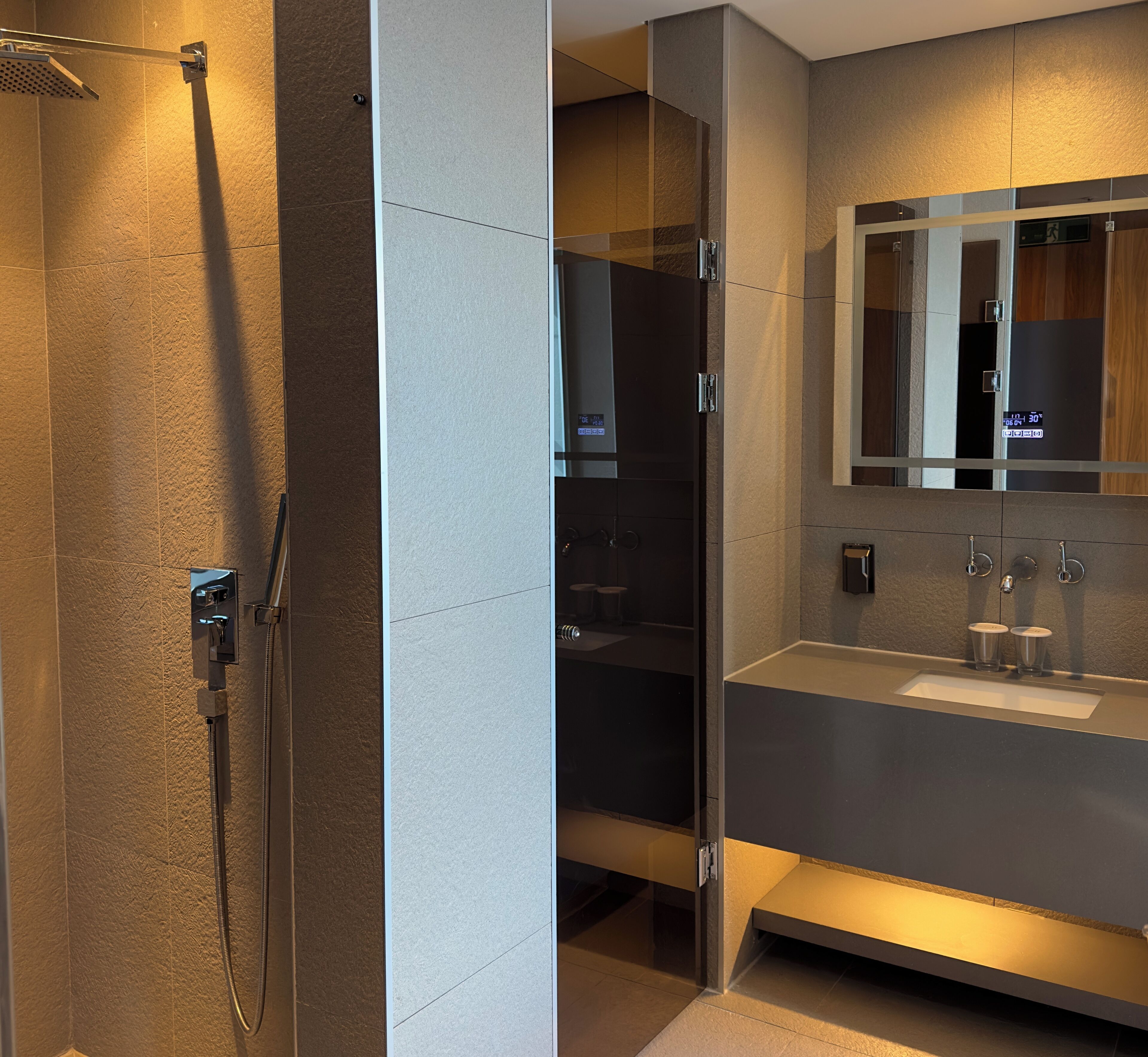 A modern bathroom with a glass-enclosed shower, a large mirror, and a vanity with a sink.