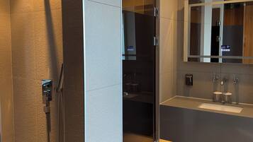 A modern bathroom with a glass-enclosed shower, a large mirror, and a vanity with a sink.