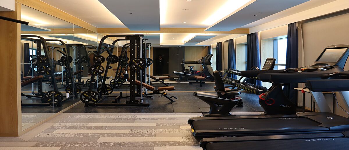 A gym with cardio machines, weightlifting equipment, and mirrors.