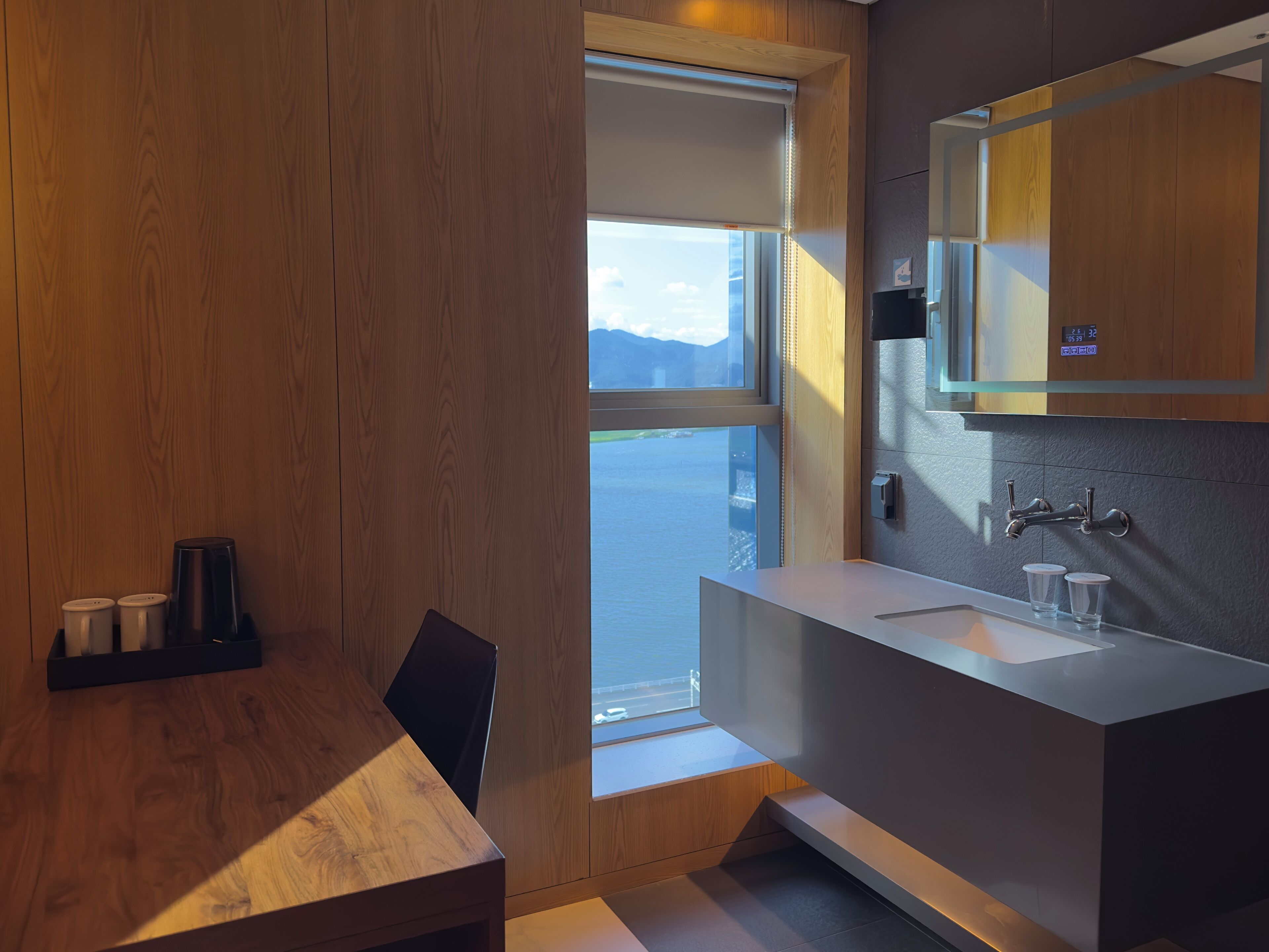 Une salle de bain moderne avec une grande fenêtre, un lavabo et un miroir.