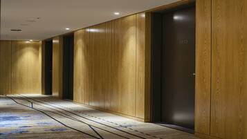 A hallway with wooden paneling and a carpet with a blue pattern.