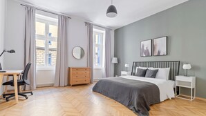 Une chambre moderne comprenant un lit, un bureau, une chaise, une commode et des œuvres d’art.