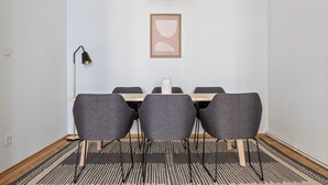 Un coin repas comprenant une table, quatre chaises grises, un lampadaire noir et une œuvre d’art abstraite encadrée accrochée au mur.