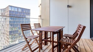 Un balcón con mesa y sillas de madera, con vistas a un paisaje urbano con edificios modernos.