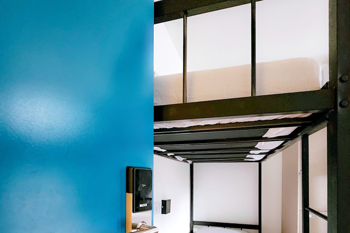 A bunk bed room with a blue door, a lock, and a control panel on the wall.