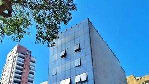 Een modern gebouw met een glazen gevel, een duidelijke ingang en een groene poort.
