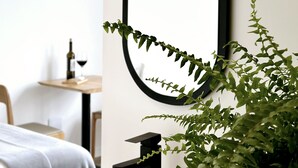 Een moderne badkamer met een zwart ovaal spiegel, een zwarte kraan en een potplant.