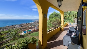 Un patio cubierto con vista al mar, mobiliario exterior y una piscina.