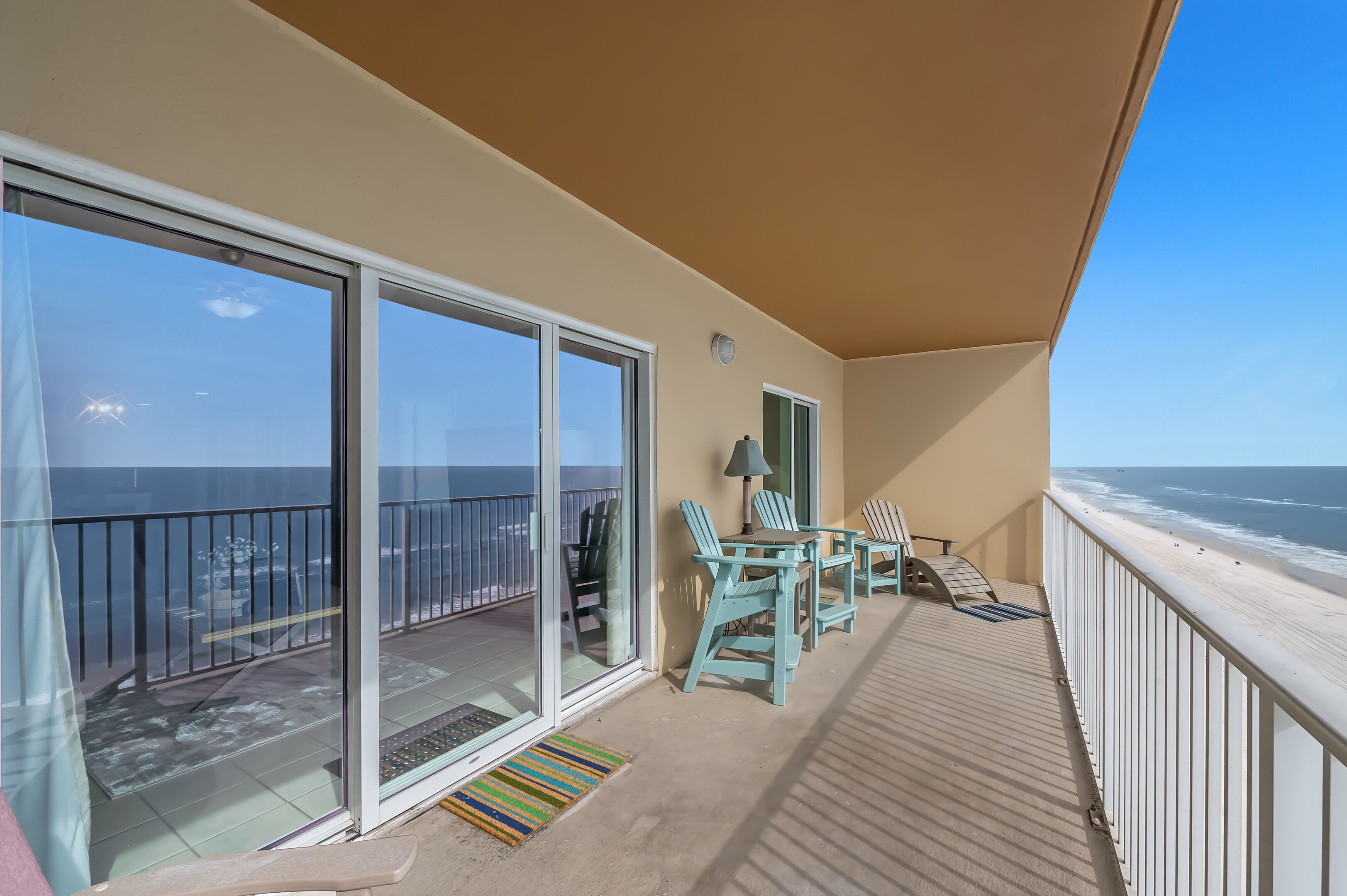 A balcony with a view of the ocean, a table with chairs, and a lamp.
