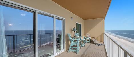 A balcony with a view of the ocean, a table with chairs, and a lamp.