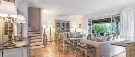 A spacious living room with a sofa set, a dining table, and a staircase leading to another level.