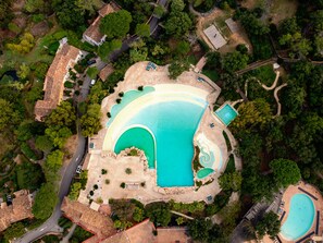An aerial view of a resort with a large central pool, multiple smaller pools, and a winding pathway. - Villa des Roses - Welkeys (Grimaud)