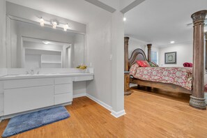 A bedroom with a large bed, a vanity with a mirror, and a wooden floor. - Hollywood Florida centrally located house for large group gathering. (Hollywood)