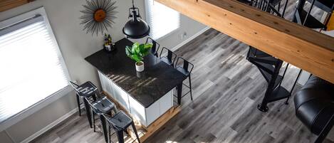 Una cocina moderna con una isla central, taburetes negros y una lámpara colgante.