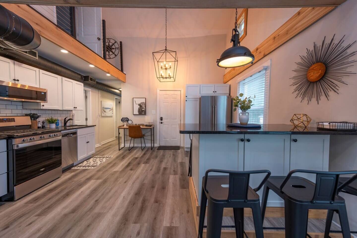 Una cocina moderna con una isla central, electrodomésticos de acero inoxidable y un comedor con mesa y sillas de madera.