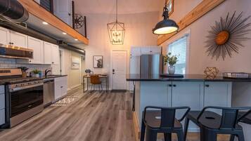 Una cocina moderna con una isla central, electrodomésticos de acero inoxidable y un comedor con mesa y sillas de madera.
