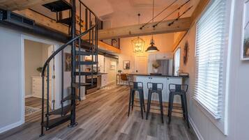 Una cocina moderna con una isla central, suelo de madera y una escalera espiral.