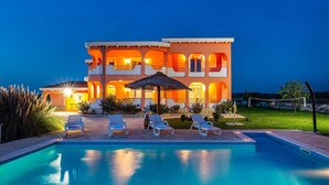 Un hôtel à plusieurs étages doté d’une piscine, d’un espace extérieur aménagé et d’une façade bien éclairée.