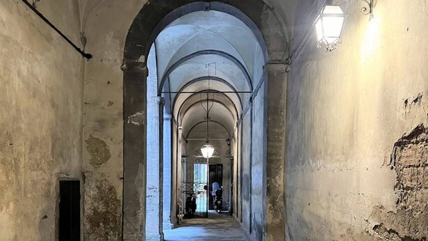 A corridor with arched ceilings and a light fixture on the wall. - CASA CONTI-nearby Piazza del Campo (Siena)