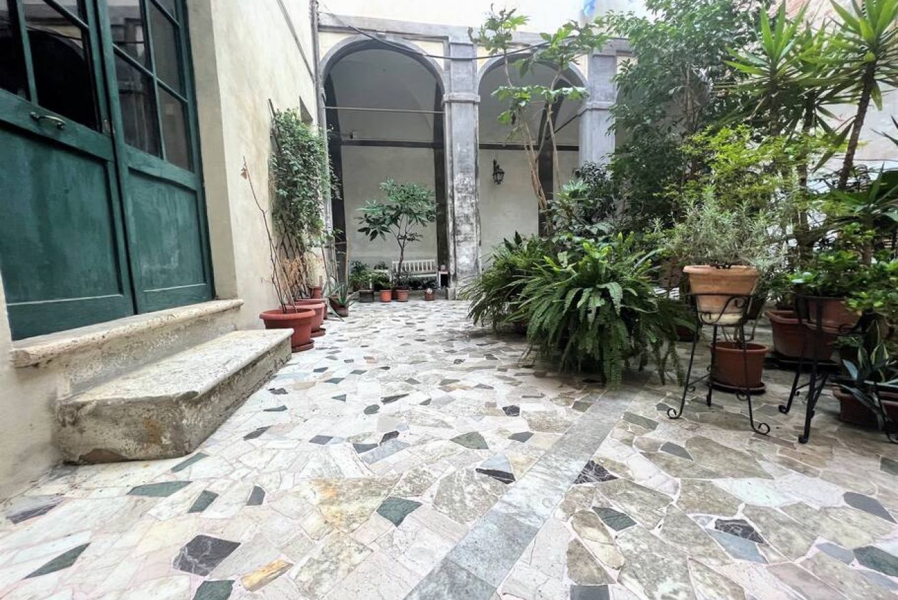 A courtyard with a tiled floor, potted plants, and a green door.