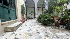 A courtyard with a tiled floor, potted plants, and a green door. - CASA CONTI-nearby Piazza del Campo (Siena)