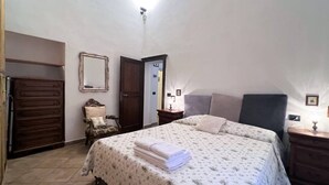 A bedroom with a bed, a dresser, a chair, and a mirror. - CASA CONTI-nearby Piazza del Campo (Siena)