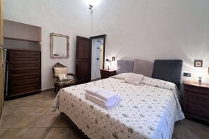 A bedroom with a bed, a dresser, a chair, and a mirror. - CASA CONTI – near Piazza del Campo (Siena)