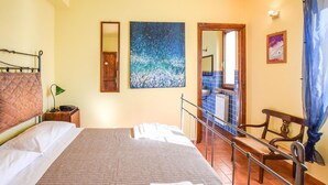 A hotel room with a bed, a nightstand, a desk, a chair, a window with a view, and a painting on the wall. - Nice home in Spoleto with kitchen (Spoleto)