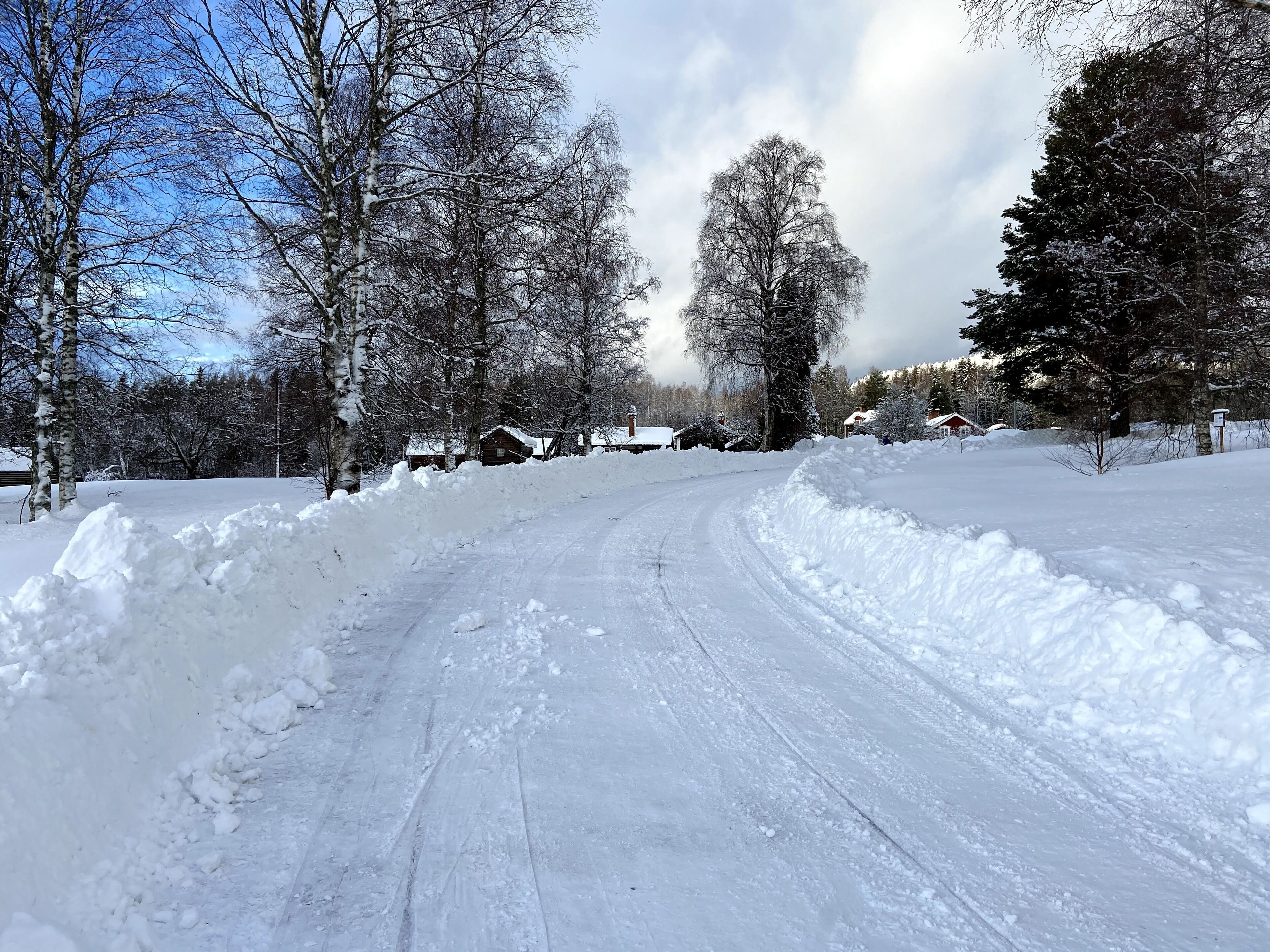 A snow-covered rural road with houses on the side.