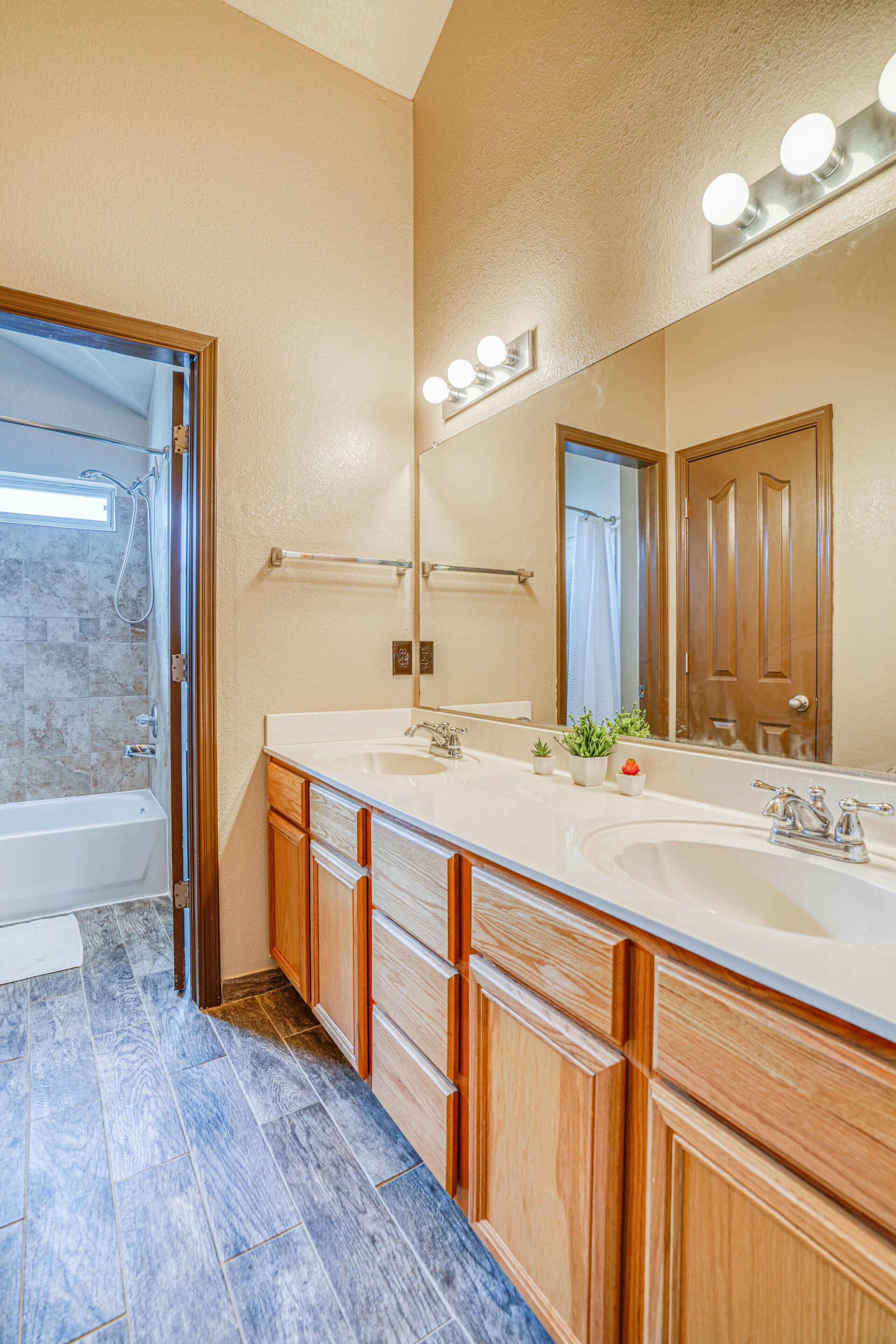 Un baño moderno con dos lavamanos, un espejo grande y muebles de madera.