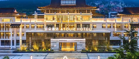 Um hotel com estilo arquitetônico tradicional, destacando uma entrada imponente e um pátio ajardinado.