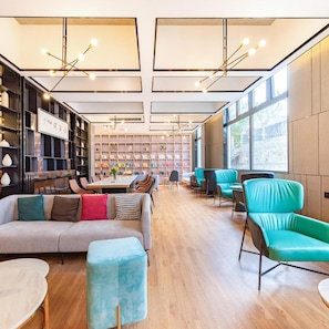 A modern interior with a sofa, chairs, a dining table, and bookshelves.