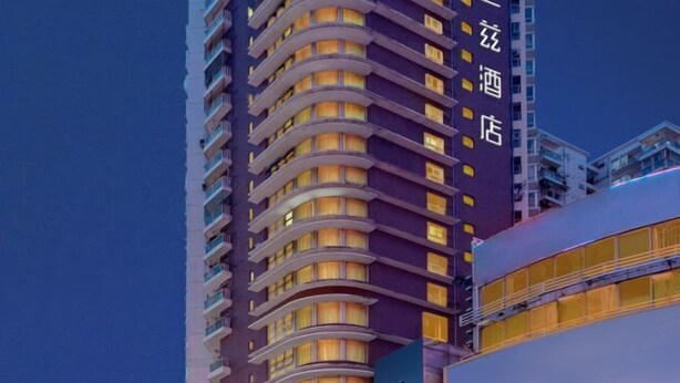 Un hotel moderno de gran altura con varios balcones y un letrero iluminado grande.