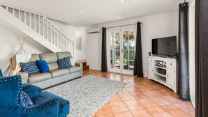 A living room with a sofa, a blue armchair, a television, and a staircase. - Family Home in Balmoral - Family Stays (Balmoral)