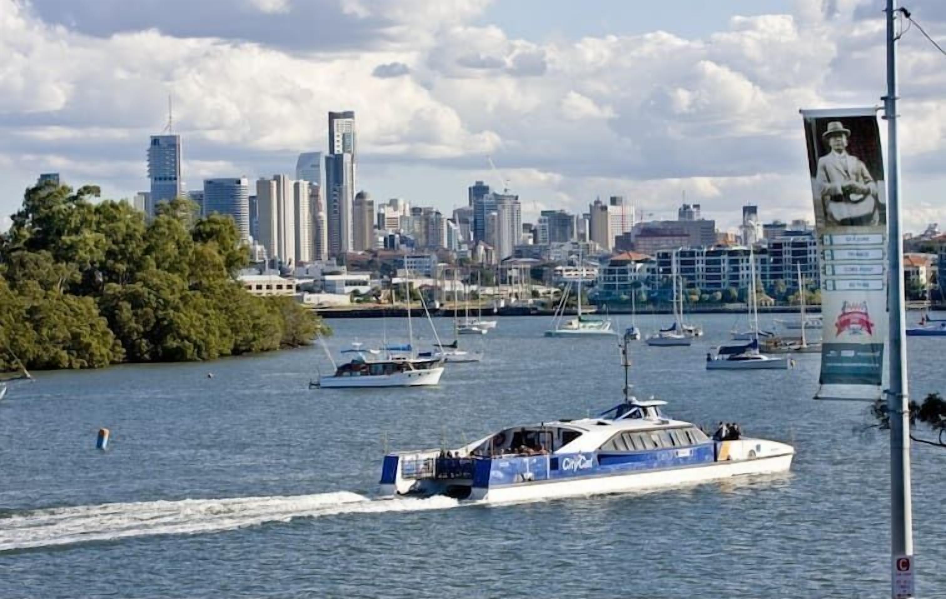 A city skyline with modern buildings and a body of water with boats.