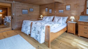 A wooden cabin bedroom with a bed, nightstands, a dresser, and framed pictures on the walls. - Chalet Bijou+ 1 OG by Interhome (Lenk)