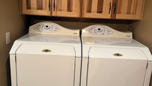 Una sala de bugaderia amb dues rentadores superposades i armaris de fusta a la part superior.