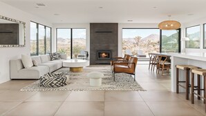 Un salon moderne doté d’une cheminée, de grandes fenêtres et offrant une vue sur le désert.