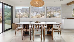 Un espace repas comprenant une grande table, six chaises et un luminaire suspendu.
